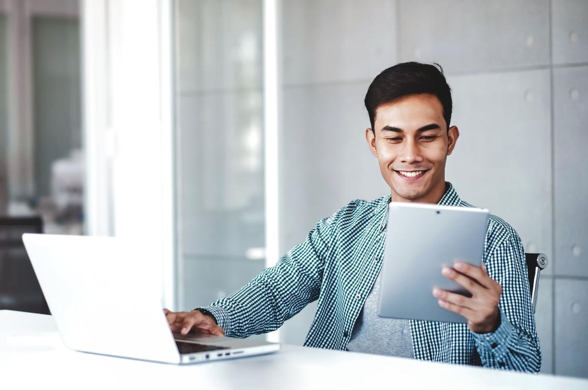 A person using a tablet and computer