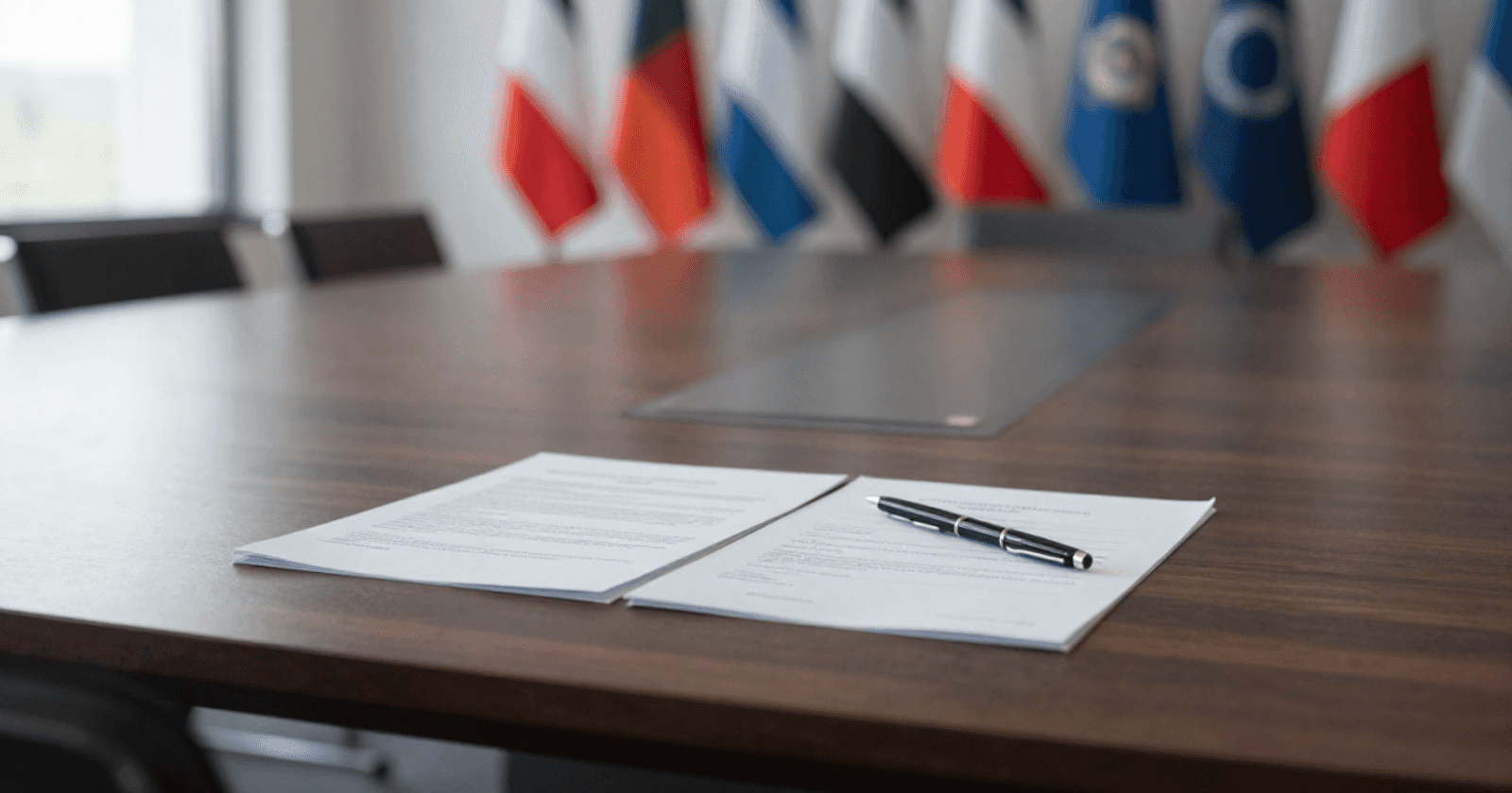 An open document on a table, with multiple flags on the back wall - representing 50 Years of OECD Responsible Business Conduct and 15 Years of the UN Guiding Principles.