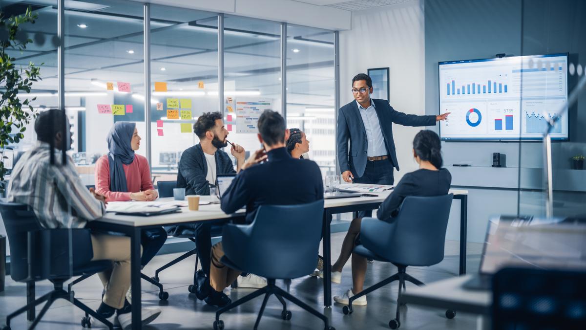 An office meeting with a diverse team in a board room presenting analytical data
